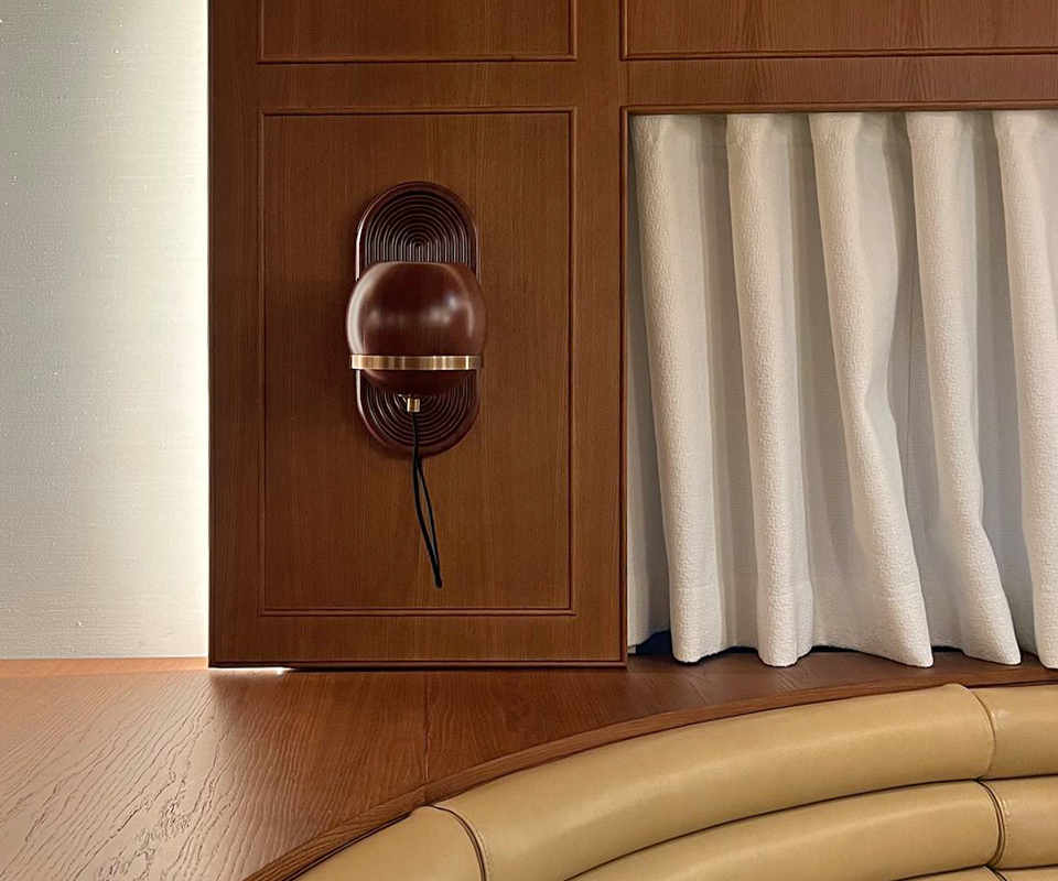 A close-up of the Fleming Wall Lamp reveals its intricate detail and design against the wood-paneled wall and curtain at Beefbar Restaurant, Luxembourg