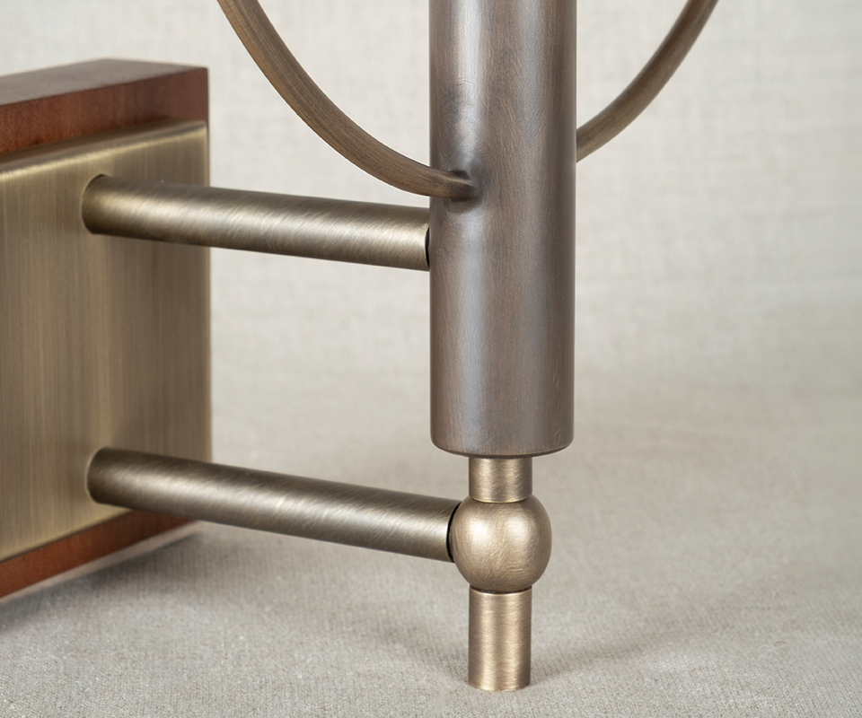 Faraday Wall Lamp Close-up detail of the Faraday Wall Lamp base by Wood Tailors Club, focusing on the aged brushed brass dual-arm structure and the smoked walnut backplate mounting.