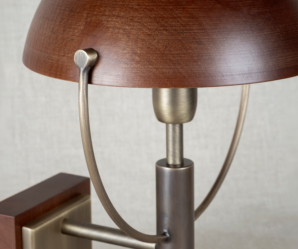 Faraday Wall Lamp Close-up detail of the top section of the Faraday Wall Lamp by Wood Tailors Club, highlighting the aged brushed brass joints and the texture of the smoked walnut dome shade.