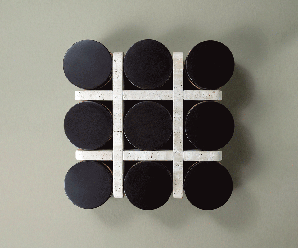 Top view of the Kensington Tic-Tac-Toe table by Wood Tailors, showing nine black round lids framed by a travertine grid against a sage green floor.