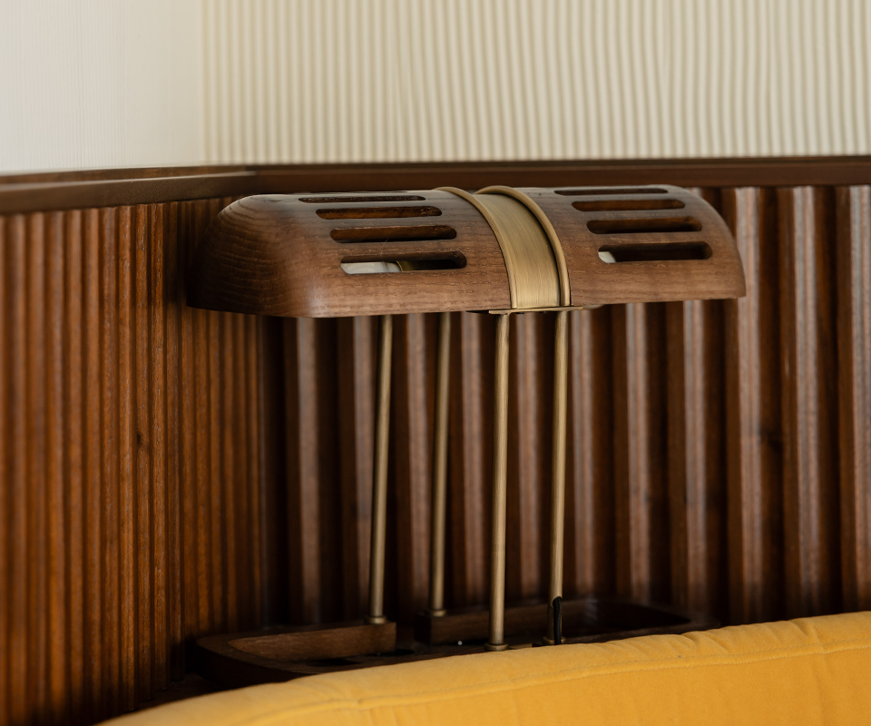 Pool House by Studio Quentin, Monte-Carlo, Monaco Close-up side view of the Turing Table Lamp with a slatted wooden shade and brass accents, placed next to a ribbed wood wall panel at Pool House by Studio Quentin, Monte-Carlo, Monaco