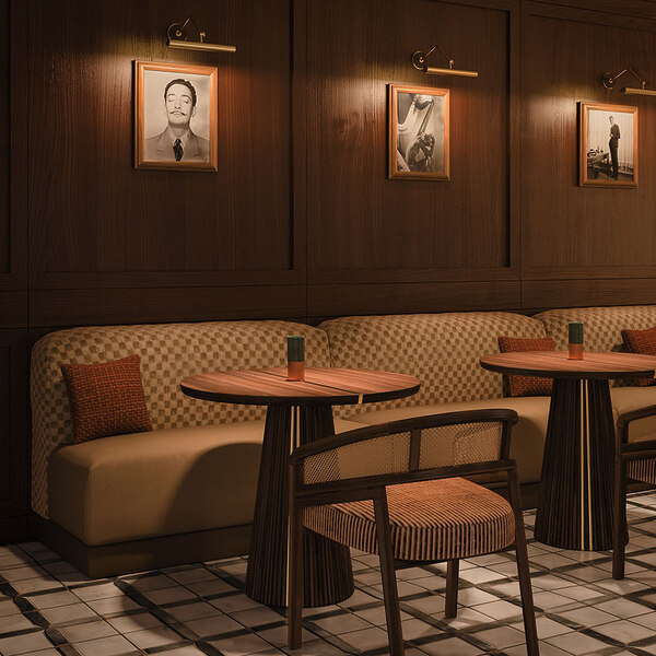 Spencer dining chair upholstered in striped fabric, with a smoked walnut wood structure and rattan details, in a restaurant setting with mood lighting, next to the Henry dining table.
