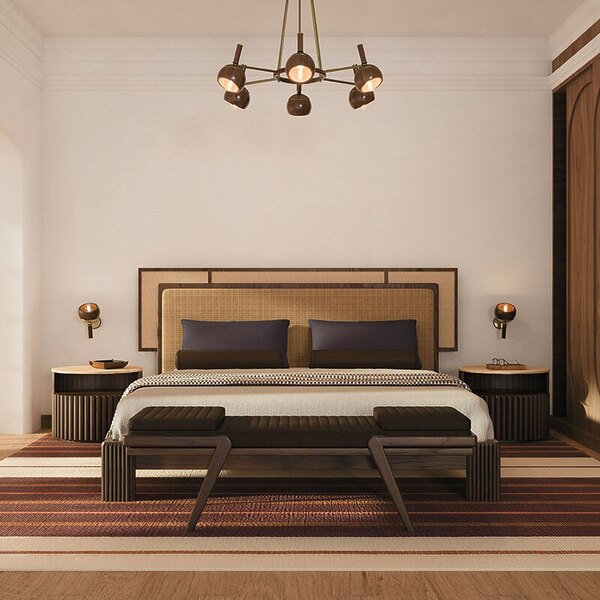 Warm-toned bedroom featuring the Forbes bed with its fabric and rattan headboard, placed between two Herbert bedside tables in smoked walnut wood. Above each bedside table, an Essen wall lamp provides soft, symmetrical ambient lighting. A Milton bench rests at the foot of the bed, while an Essen suspension lamp hangs overhead, enhancing the room’s warm, refined, and cohesive atmosphere. The space embraces the rattan bedroom furniture trend.