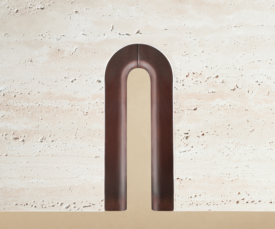 A top-down close-up of the Grenville Center Table surface. The shot highlights the organic, porous texture of the cream travertine stone. A dark smoked walnut wood leg is shown interlocking with the tabletop through a perfectly rounded, U-shaped cutout. A thin, precise outline of brushed brass provides a metallic transition between the wood and the stone.