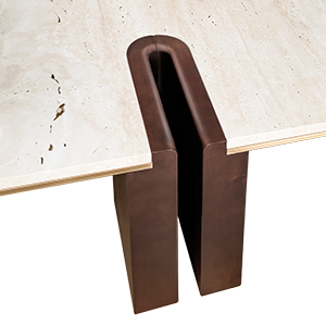 A macro close-up of the Grenville Center Table's joinery. The image shows a deep U-shaped groove carved into the dark smoked walnut wood, perfectly interlocking with the edge of the cream travertine top. A thin, elegant layer of brushed brass sits flush between the wood and the stone.