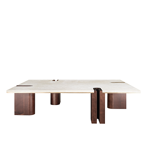 A wide front view of the Grenville Center Table featuring a thick, rectangular cream travertine top. The structure consists of four chunky, asymmetrical legs made of dark smoked walnut wood. One leg features a distinctive vertical U-shaped cutout that notches into the stone top, revealing a thin brushed brass inlay along the edge.
