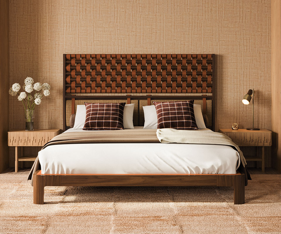 Herschel table lamp in smoked walnut wood and aged brushed brass paired with a Campbell bedside table in oak wood. O'Connell II Bed with a headboard featuring leather details in Prestige fabric from Élitis, set in a bedroom with Élitis Abaca wallpaper and Ralph Lauren Wallace throw pillows.