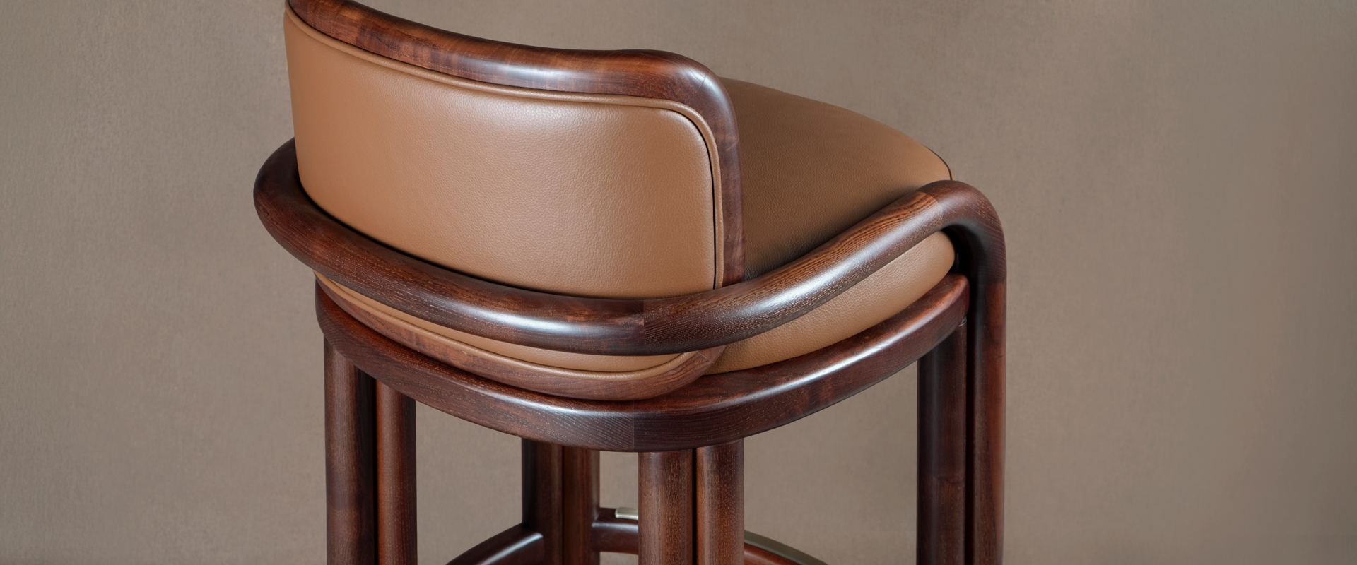 James Bar Chair Close-up detail shot of the James Bar Chair showing the curved smoked walnut wood joint structure and fine tan genuine leather upholstery.