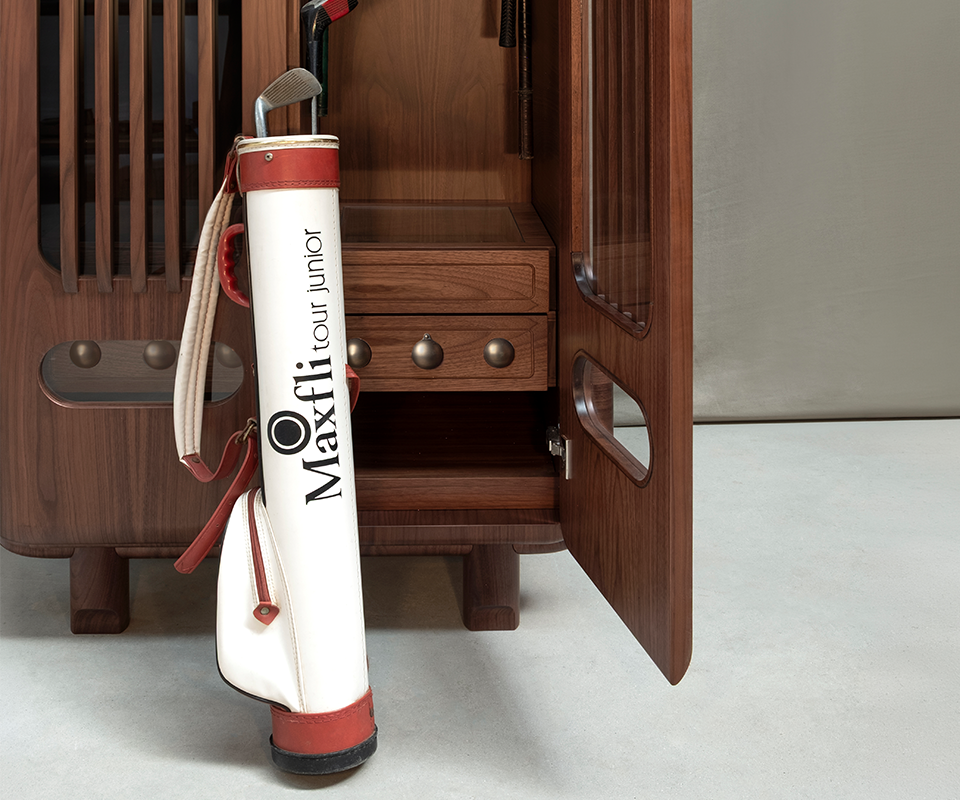 A medium shot of the open smoked walnut locker base. A vintage white and red leather golf bag is placed in front, showing the scale of the interior storage compartment.