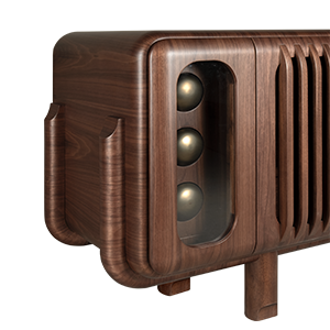 A perspective close-up of the Kennedy Sideboard's corner, emphasizing its mid-century modern profile. The shot highlights the walnut wood's rich grain and the unique, pipe-like curved wooden supports on the side. Three decorative brass spheres are visible through a glass panel at the front, positioned next to the unit's signature vertical slats.