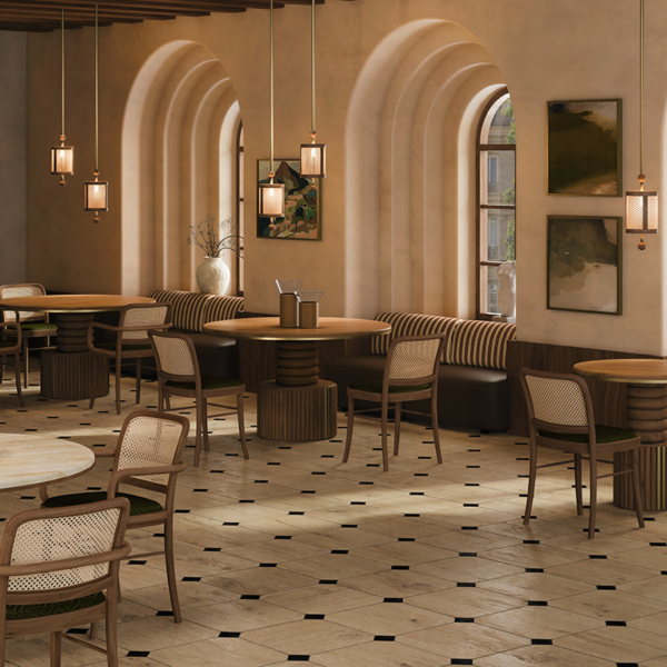 Luxurious restaurant dining room furnished with multiple Stuart I Dining Tables by Wood Tailors Club, paired with wooden chairs with woven backrests, plush banquette seating, arched windows, and warm pendant lights.
