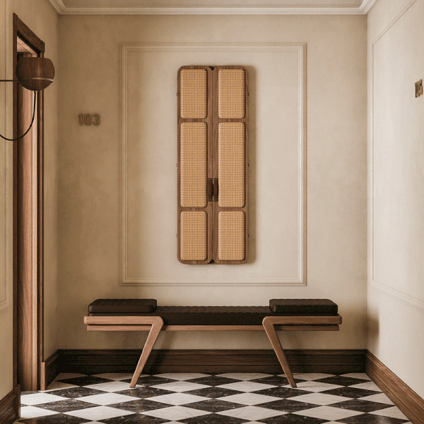 Tom folding mirror opening and closing in a hotel corridor with wooden icons, featuring upholstered doors, leather handles, and an interior mirror. The floor displays a diamond checker pattern. Below the mirror is the Milton Bench, with an oak structure and leather seat. Flaming wall lamp and Faraday wall lamp in smoked walnut wood complete the setting.